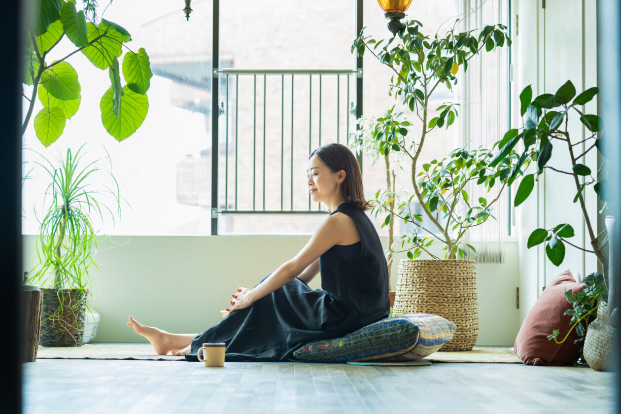 A woman relaxing surrounded by foliage plants | ソフィアウッズ・インスティテュート公式ブログ